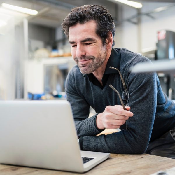 Businessman using laptop in a factory